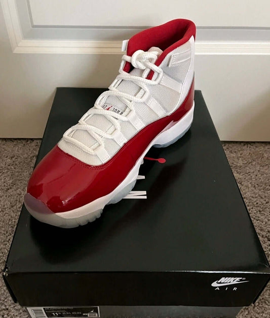 Air Jordan 11 “Win Like ’96” sneaker displayed on its box, featuring a white and red design and classic style.