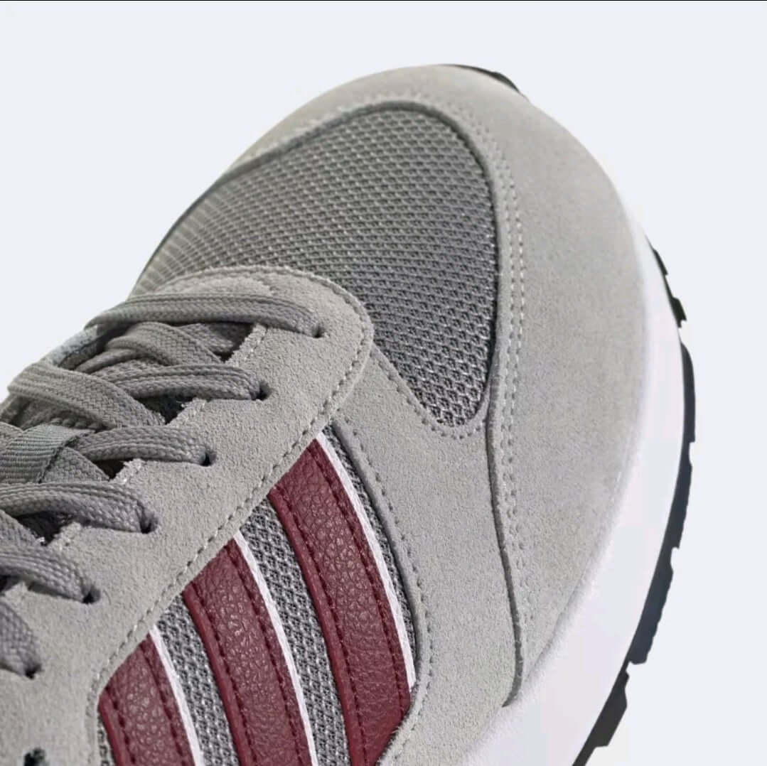 Close-up of Adidas Run 80s men shoes showcasing grey mesh and Shadow Red accents for retro running style.