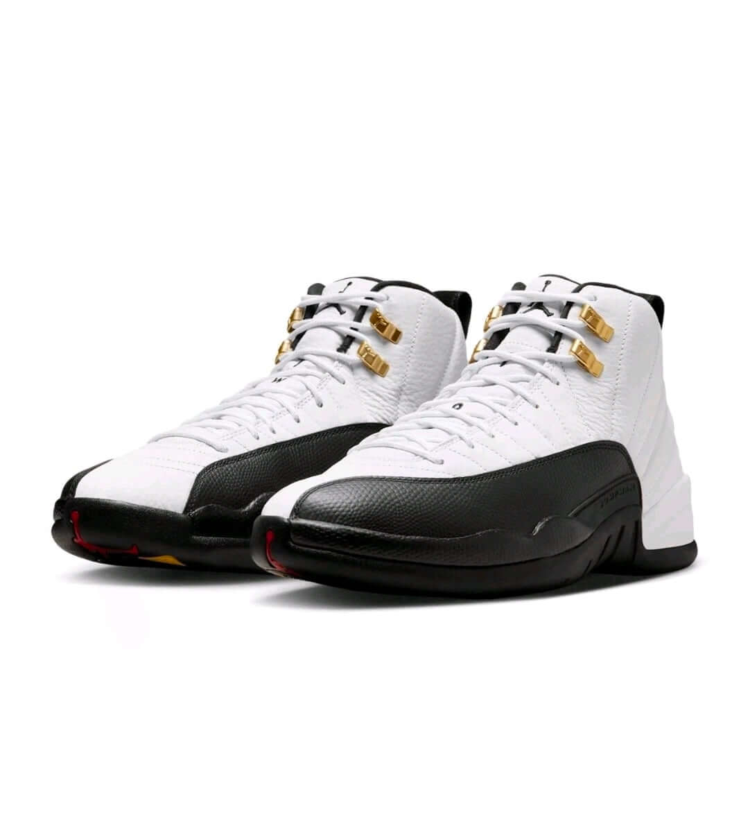 Air Jordan 12 “Taxi” sneakers displayed in a stylish black and white colorway with gold detailing.
